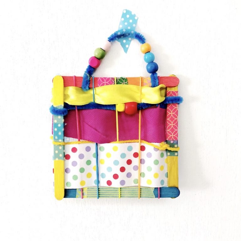 Simple weaving project for kids. Create colourful works of art using craft sticks and ribbon scraps #finemotor #weaving #kidscrafts