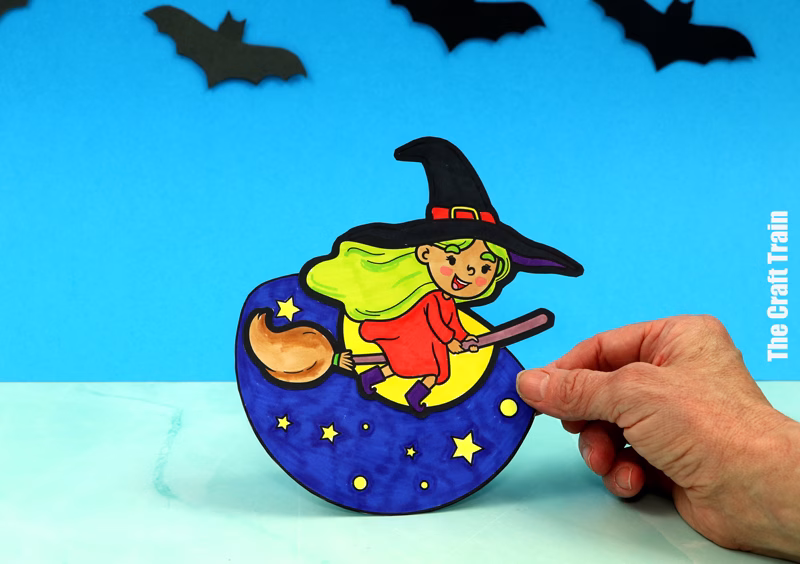 Witch Halloween rocker craft for kids. A hand is tilting the rocker, ready to release it so it can rock, rock, rock.