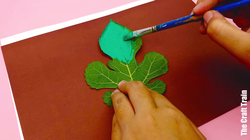 Hand painting leaf to create leaf prints