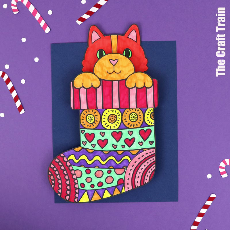Kids printable art project featuring an orange kitten peeking out of pattern art Christmas stockings