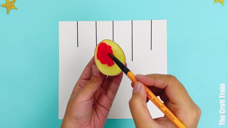 Potato stamp Christmas bauble artwork steps - cover potato stamp with paint using a brush